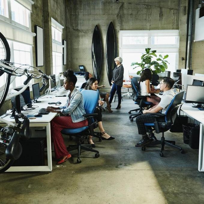 Un grupo de personas que trabajan en un espacio de oficina con escritorios y bicicletas en las que están conversando